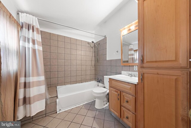 full bathroom featuring vanity, tile patterned flooring, toilet, shower / bath combo, and tile walls