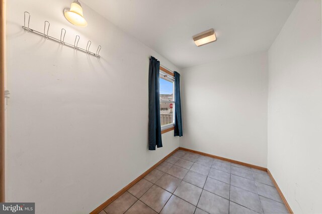 spare room with light tile patterned floors and baseboards