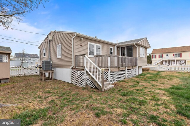 rear view of property featuring a yard, a fenced backyard, a deck, and central AC