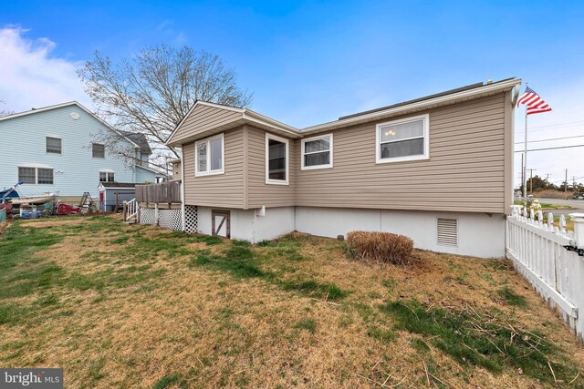 rear view of house featuring fence and a lawn