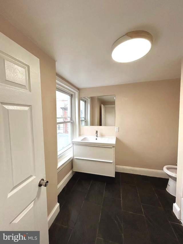 half bath with toilet, vanity, baseboards, and tile patterned flooring