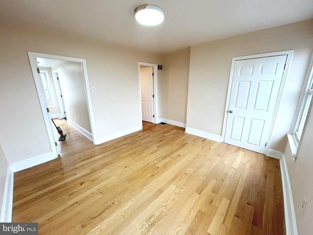 spare room featuring baseboards and light wood-type flooring