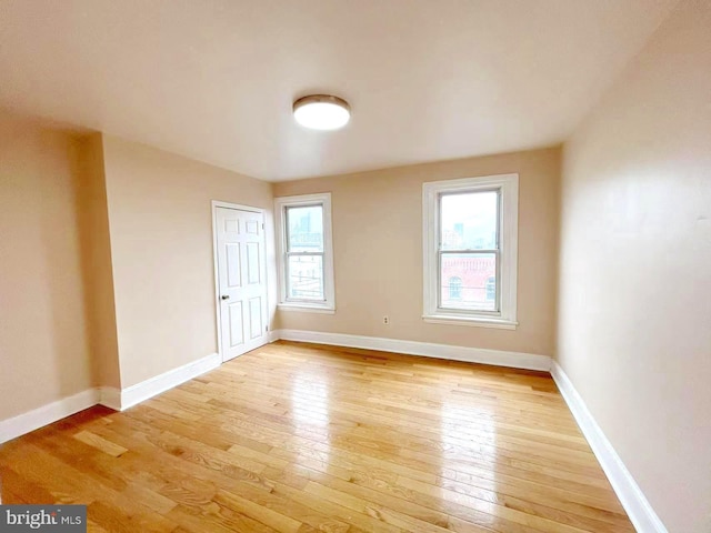spare room with baseboards and light wood-style floors