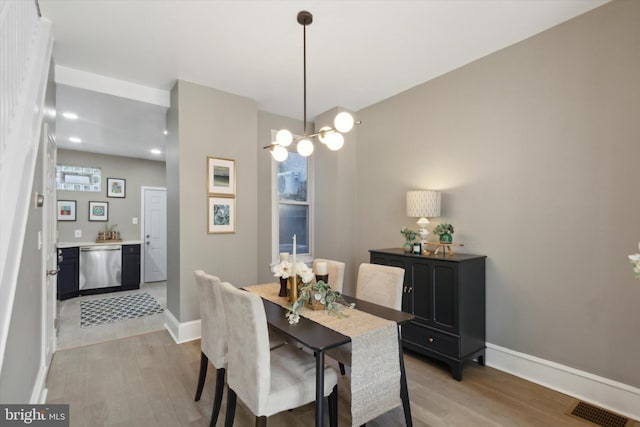 dining area with a notable chandelier, light wood finished floors, visible vents, and baseboards
