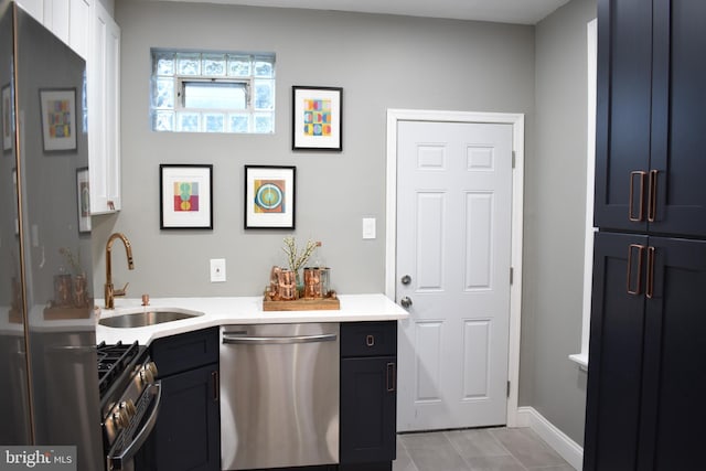 interior space featuring light tile patterned floors, dishwasher, a sink, gas range oven, and baseboards
