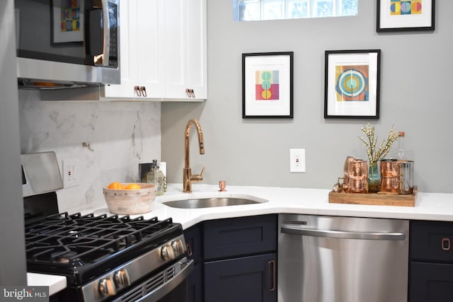kitchen with tasteful backsplash, a sink, light countertops, white cabinetry, and stainless steel appliances