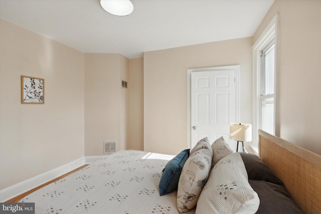 bedroom featuring visible vents, baseboards, and wood finished floors