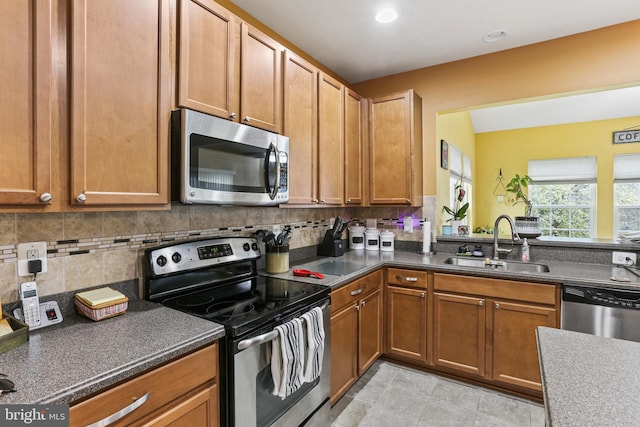 kitchen featuring stainless steel appliances, decorative backsplash, a sink, and dark countertops
