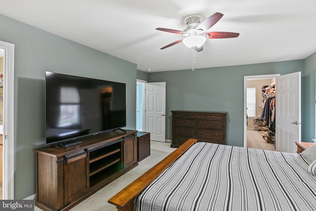 bedroom featuring a closet, ceiling fan, a walk in closet, and light colored carpet
