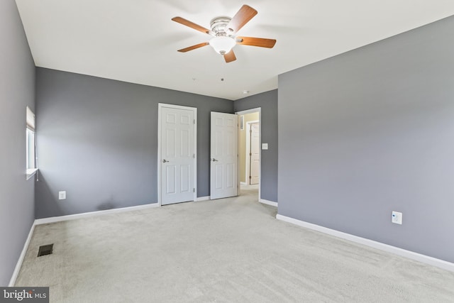 unfurnished bedroom with light carpet, visible vents, baseboards, and a ceiling fan