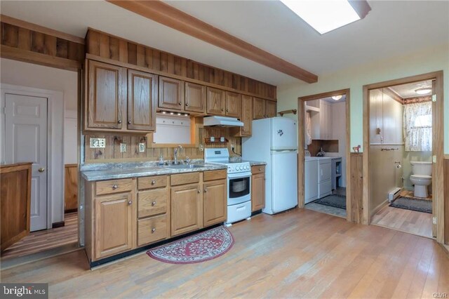 kitchen with a sink, white appliances, under cabinet range hood, light wood finished floors, and washing machine and clothes dryer