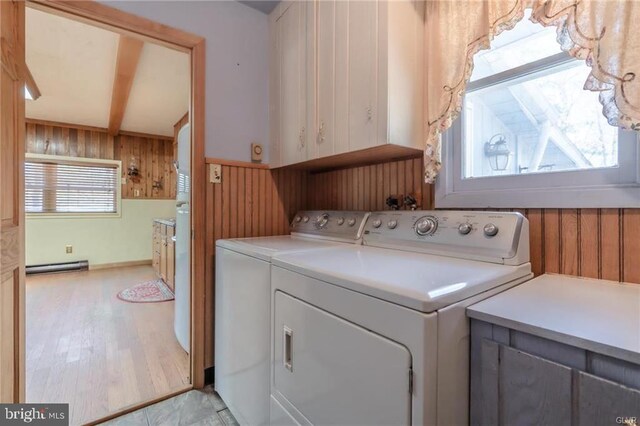 laundry room featuring a baseboard radiator, light wood-type flooring, cabinet space, wood walls, and washing machine and dryer