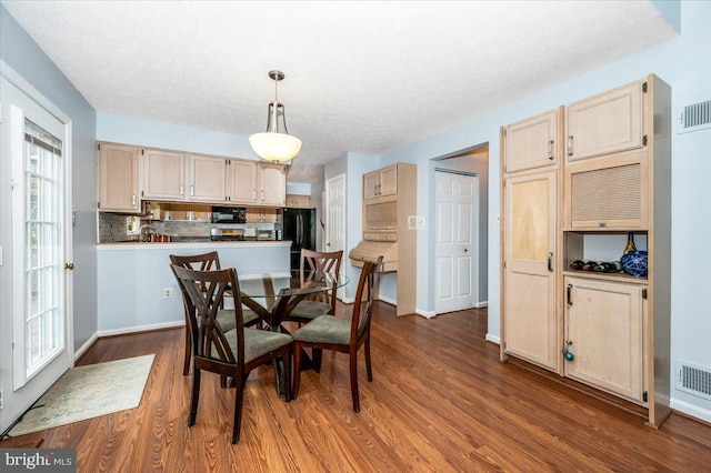 dining space with a textured ceiling, dark wood-style flooring, baseboards, and visible vents