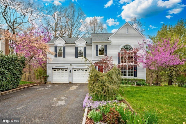 traditional-style house featuring a garage, driveway, and a front lawn