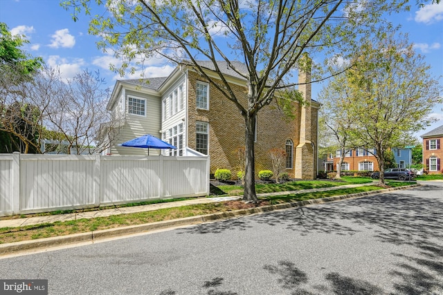 709 Pilot House Dr, Annapolis, MD 21401 - view of side of property featuring fence, a chimney, and brick siding