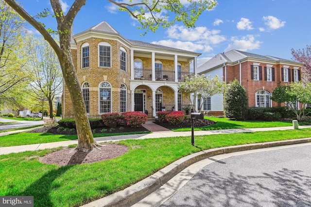 709 Pilot House Dr, Annapolis, MD 21401 - view of front of house with brick siding, covered porch, a front lawn, and a balcony
