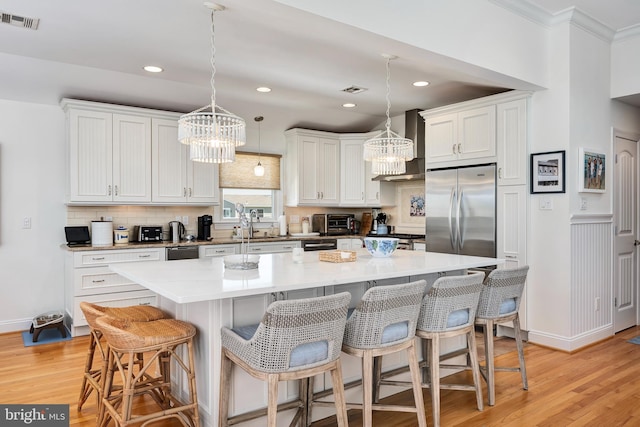 1082-E Long Beach Blvd, Long Beach Township, NJ 08008 - kitchen featuring built in fridge, a chandelier, wall chimney range hood, light wood-type flooring, and ornamental molding