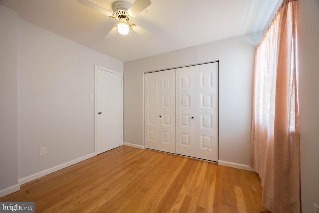 unfurnished bedroom with light wood-style flooring, baseboards, a closet, and a ceiling fan