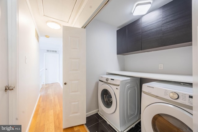 laundry area featuring cabinet space, separate washer and dryer, baseboards, and light wood-style flooring