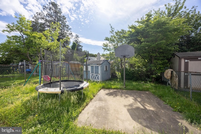 fenced backyard featuring a storage unit, a trampoline, a playground, an outdoor structure, and a patio area