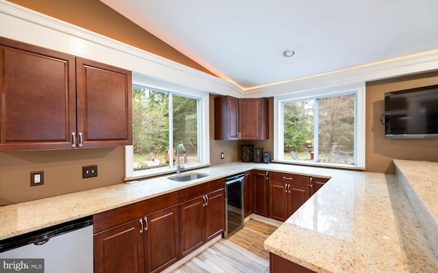 kitchen with a wealth of natural light, vaulted ceiling, dishwashing machine, and a sink