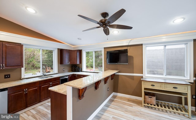 kitchen with light stone counters, a breakfast bar, a ceiling fan, a sink, and a peninsula