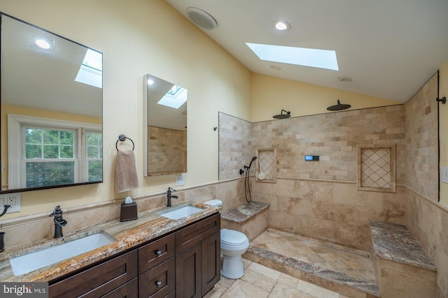 full bathroom with vaulted ceiling with skylight, stone tile floors, toilet, and a sink