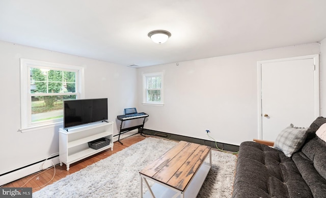 living room with a baseboard heating unit, plenty of natural light, and wood finished floors