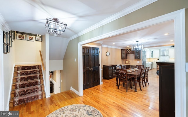 dining space with light wood-type flooring, baseboards, a notable chandelier, stairs, and crown molding