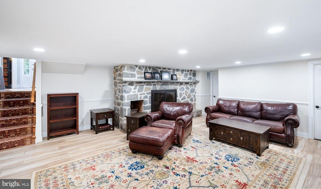 living area featuring recessed lighting, wood finished floors, and a stone fireplace
