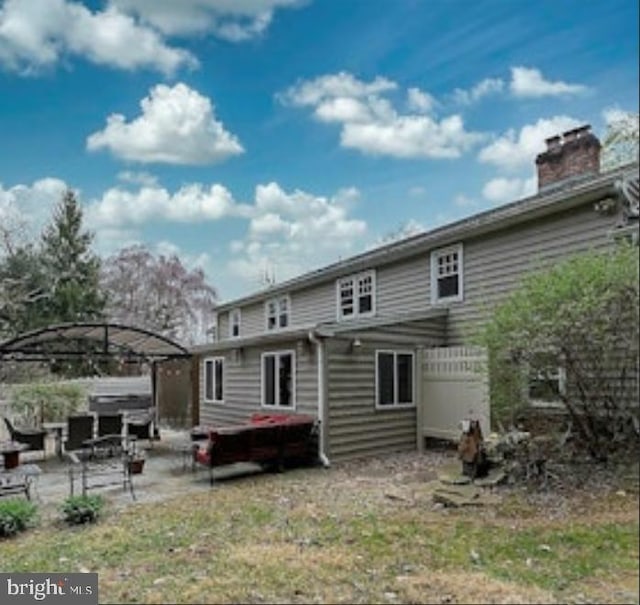 rear view of property with a chimney and a patio area