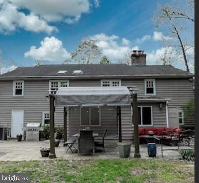 rear view of property featuring outdoor lounge area, a patio area, and a chimney