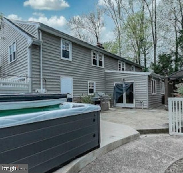 rear view of house with a patio area and a hot tub