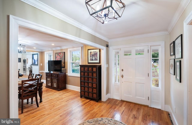 entryway featuring light wood-style flooring, baseboards, a notable chandelier, and ornamental molding