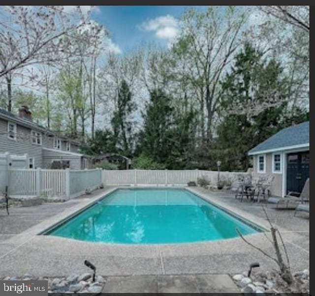 view of pool featuring a fenced in pool, an outbuilding, a patio, and fence
