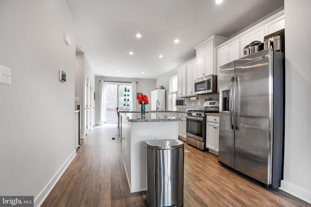 kitchen with stainless steel appliances, white cabinetry, wood finished floors, and a kitchen island
