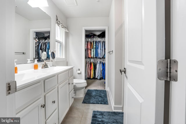 full bathroom with double vanity, a spacious closet, tile patterned floors, toilet, and visible vents