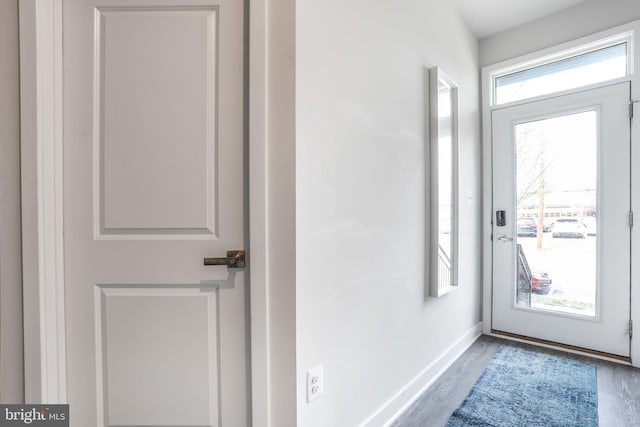 doorway with baseboards and wood finished floors