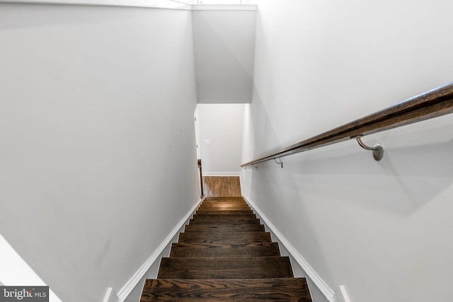 staircase featuring baseboards and wood finished floors
