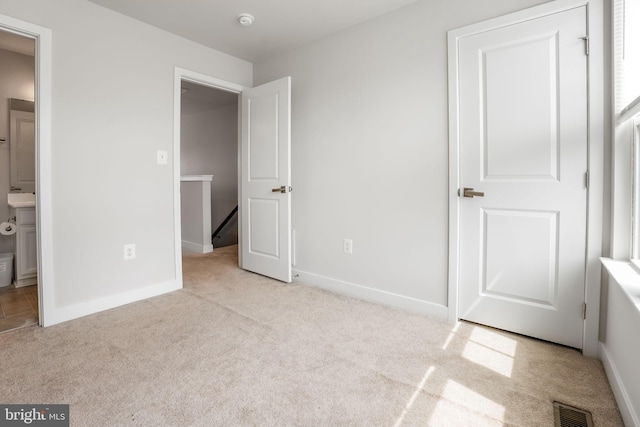 unfurnished bedroom with carpet, visible vents, and baseboards