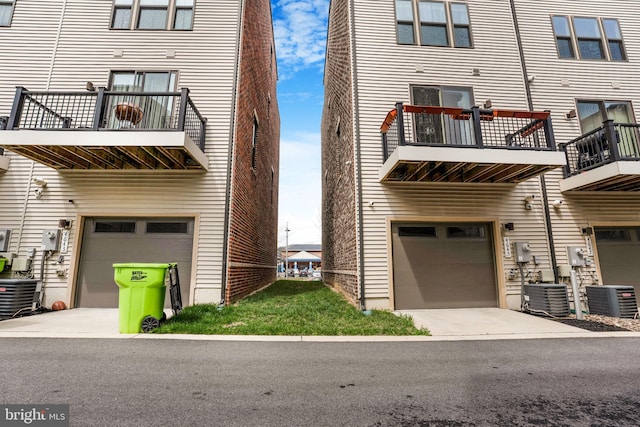 exterior space with an attached garage, cooling unit, and concrete driveway
