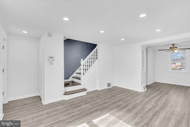 unfurnished living room featuring wood finished floors, visible vents, recessed lighting, and stairs