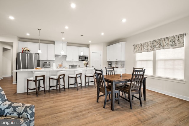 dining space with light wood-style floors, baseboards, a toaster, and recessed lighting