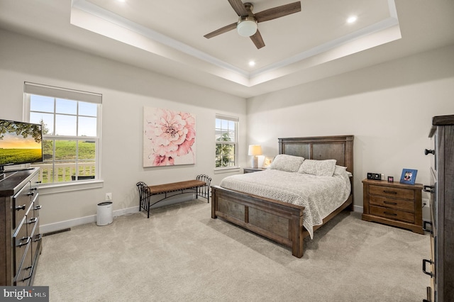 bedroom featuring a raised ceiling, light carpet, baseboards, and multiple windows