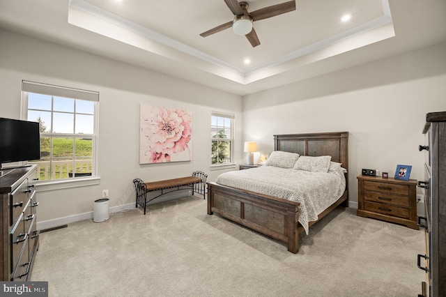 bedroom with baseboards, multiple windows, a tray ceiling, and light colored carpet