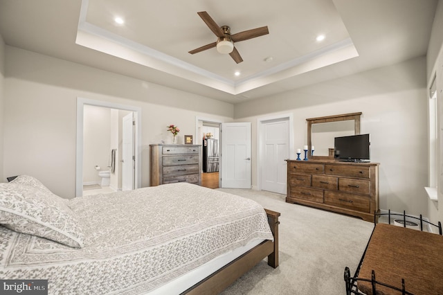 bedroom with light carpet, recessed lighting, ensuite bathroom, and a raised ceiling