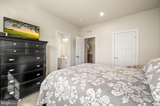 carpeted bedroom featuring ensuite bathroom and visible vents