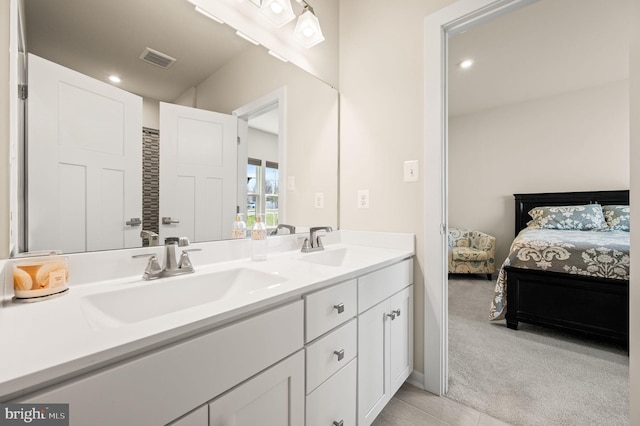 ensuite bathroom featuring double vanity, recessed lighting, ensuite bathroom, visible vents, and a sink