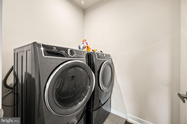 clothes washing area with baseboards, washing machine and dryer, tile patterned flooring, and laundry area