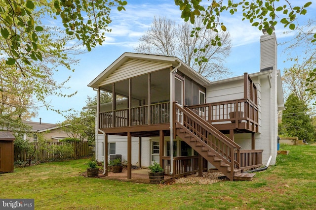 rear view of house with a lawn, a chimney, a sunroom, and a deck